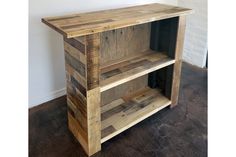 a wooden shelf sitting on top of a floor next to a white wall and brown floors