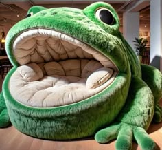 a large stuffed frog sitting on top of a wooden floor