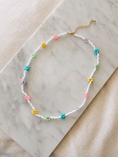 "This hand beaded flower necklace features rainbow or pastel flowers and measures 16\" at its smallest. Necklace is adjustable up to 18\" I love this necklace layered with other gold chains or worn alone to spruce up jeans and a t-shirt. Strung on elastic jewelry string and has a gold plated lobster clasp closure. Message me with any questions!" Spring Beaded Necklaces With Flower Charm And Round Beads, Handmade Dainty Beaded Necklaces For Spring, Spring Beaded Necklace With Flower Charm And Round Beads, Spring Flower Charm Beaded Necklace As Gift, Handmade Dainty Beaded Necklace For Spring, Spring Beaded Necklace With Flower Charm, Spring Flower Charm Necklace With Round Beads, Dainty Beaded Necklaces For Spring, Dainty Spring Necklace With Round Beads