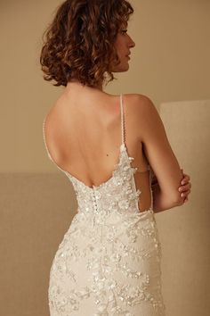 a woman in a wedding dress is looking back at the camera while she wears an open - back gown