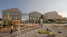 people are walking around in front of a building that has many windows and lots of plants