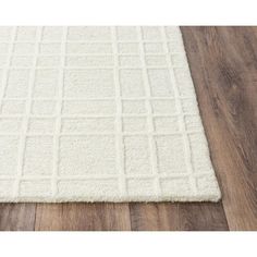 a white rug on top of a wooden floor next to a hard wood flooring