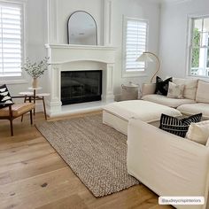 a living room with white furniture and a fireplace