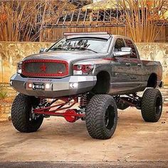 a truck with big tires parked in front of a building