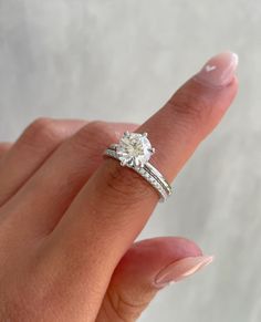 a woman's hand holding an engagement ring with two bands on it and a diamond in the middle