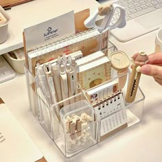 a person is holding a pen and taking notes from a clear holder on a desk