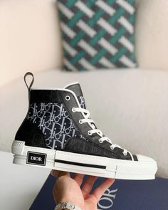 Embrace a blend of classic and contemporary style with these high-top sneakers inspired by the iconic Dior B23. Featuring a sleek black upper adorned with the signature Dior Oblique pattern, these shoes exude understated luxury. The contrasting white sole with a black stripe adds a sporty touch, while the high-top silhouette provides ankle support and a fashion-forward edge. Luxury High-top Sneakers With Contrast Sole For Streetwear, Medium Fit High-top Sneakers With White Sole, Designer High-top Sneakers With Contrast Sole, Luxury Lace-up High-top Sneakers With Contrast Sole, Modern Medium Fit High-top Sneakers For Streetwear, Luxury High-top Sneakers With Contrast Sole, Designer High-top Sneakers For Streetwear, Designer Lace-up High-top Sneakers With Boost Midsole, Luxury High-top Sneakers With Boost Midsole For Streetwear