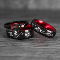 two black and red wedding rings with crosses on the sides, one has an evil symbol