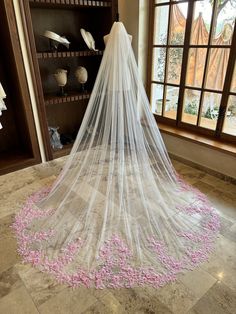 a white wedding veil with pink flowers on the floor