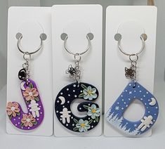 three key chains with flowers and letters on them