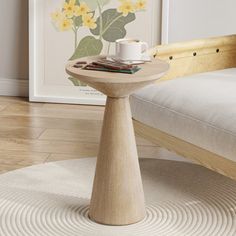 a small table with a cup on it in front of a bed