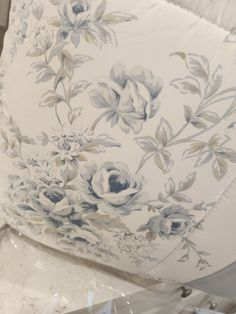 a white pillow with blue flowers on it sitting on top of a table next to other items