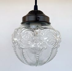 a glass light hanging from a ceiling fixture with flowers on the front and side of it