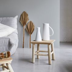 three white vases are sitting on small stools in front of a couch and coffee table