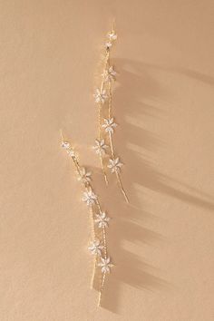 two white flowers are attached to gold ear pins