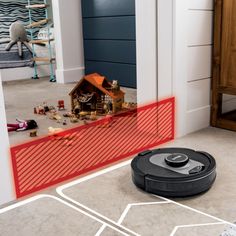 a robotic vacuum cleaning the floor in front of a house with red lines on it