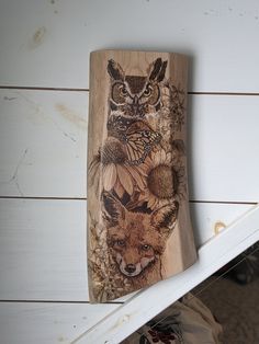 a wooden plaque with an owl and other animals painted on it's side next to a window