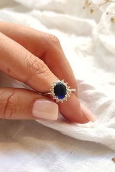 a woman's hand with a ring on it and a blue stone in the middle