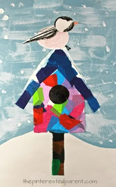 a bird sitting on top of a colorful birdhouse made out of construction paper and colored blocks