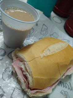 a half eaten sandwich and a cup of coffee on a wrapper with paper wrapping