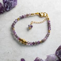 Elegant Amethyst and gold bracelet hand crafted with care and attention to detail using AA 4mm faceted Amethyst beads, gold fill accent beads and a gold plated simulated twisted wire central bead. The bracelet is constructed using quality 19 strand nylon coated beading wire which is both flexible for a comfortable wear and extremely durable. The bracelet measures 17.5cm and is fastened with a gold plated lobster claw clasp and a 30mm extension chain for an adjustable fit up to 20 cm. Amethyst is Gold Charm Bracelet With Natural Stones Gift, Spiritual Gold Charm Bracelet With Gemstones, Spiritual Gold Gemstone Charm Bracelet, Spiritual Amethyst Gold Bracelets, Gold Crystal Bracelet With Gemstone Beads As Gift, Gold Amethyst Bracelets For Healing, Spiritual Gold Charm Bracelet With Gemstone Beads, Amethyst Bracelets In Yellow Gold For Gift, Amethyst Yellow Gold Bracelets For Gift