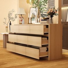 a wooden cabinet with drawers and vases on top in a room that has hard wood flooring