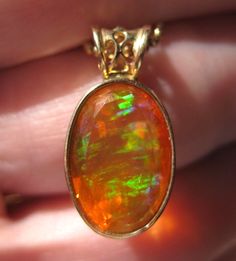 Absolutely gorgeous Mexican Fire Opal filled with colors against orange set in thick substantial 14k yellow gold  Ladies yellow gold fire opal pendant containing 1 natural Mexican fire opal set in a yellow gold bezel at a low height. The fire opal measures approx 9.5 x 14mm and has flashes of greens, blues and purple colors. The pendant has a custom bale with a design and weighs approx 2.1 grams. simply set, minimalist with filigree on the bale  pendant only, no chain included, final photo included just to show how you may choose to style the pendant measurements above, no hallmarks please ask any questions prior to purchase  please look at my other listings  I will ship quickly after payment received Mexican Opal, 2024 Aesthetic, Mexican Fire Opal, Gold Filigree, Payment Received, Opal Pendants, Fine Jewellery Necklace, Fire Opal, The Fire