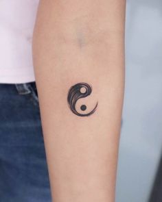 a woman's arm with a tattoo on it that has a yin symbol in the middle