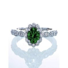 a green and white diamond ring on a white surface with reflection in the middle,