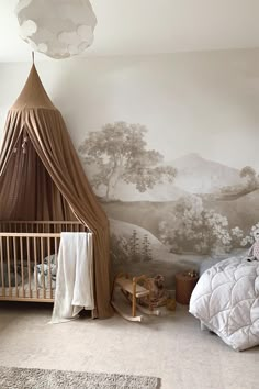 a baby's room with a bed, crib and wall mural