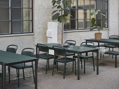 tables and chairs in front of a white brick building with large windows on the side