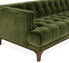 a green velvet couch with wooden legs