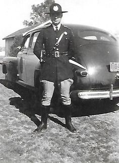 a man in uniform standing next to an old car