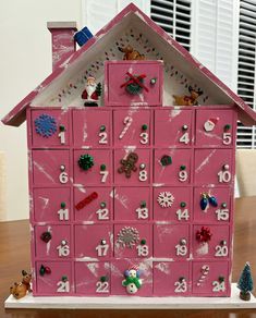 a pink house shaped like a calendar with christmas decorations on the front and numbers on the outside