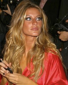 a woman in a red dress holding a cell phone and looking at the camera while she is surrounded by photographers