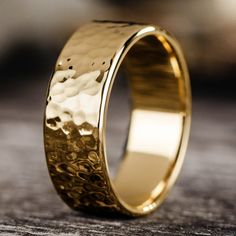 a gold wedding ring on top of a wooden table with the light reflecting off it's surface