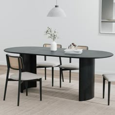 a dining table with four chairs and a vase on it, in front of a white wall