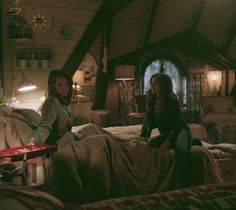 two young women sitting on top of a bed in a bedroom next to each other