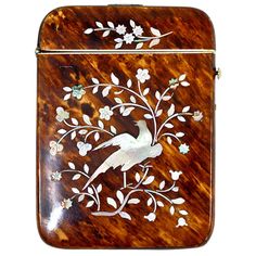 a wooden box with a bird painted on the side and flowers in the middle, sitting on a white background