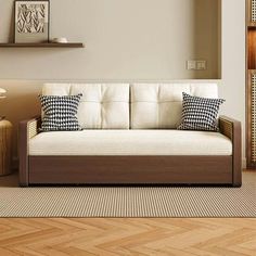 a white couch sitting on top of a wooden floor next to a wall mounted clock