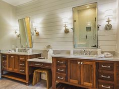 a bathroom with two sinks, mirrors and lights on the wall above them is shown