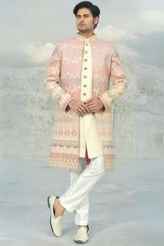 a man in a pink and white sherwa with his hands on his hips