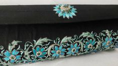 "The perfect wedding purse! A sophisticated and feminine black silk clutch bag, expertly hand embroidered by zardozi artisans. A profusion of petit blue silk flowers are inlaid with emerald gemstones. Each delicate petal and leaf is meticulously outlined with a glittery silver metallic thread, to give a sparkly, opulent 3D effect. Crowned by a beautifully embroidered blue medallion with an emerald cabochon. The word Zardozi means \"gold thread\". It is an elaborate and intricate embroidery art f Elegant Black Hand Embellished Clutch, Elegant Black Hand-embellished Clutch, Black Hand Embellished Clutch For Wedding, Festive Formal Clutch With Intricate Embroidery, Traditional Embroidered Evening Bag For Formal Occasions, Traditional Embroidered Evening Bag For Formal Events, Elegant Embroidered Potli Bag For Formal Occasions, Traditional Embroidered Formal Evening Bag, Formal Clutch With Zari Work