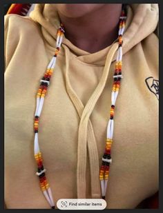 a person wearing a yellow hoodie and some beads on their necklaces with the words find similar items