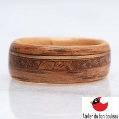 a close up of a wooden ring on a white surface with a red bird in the background