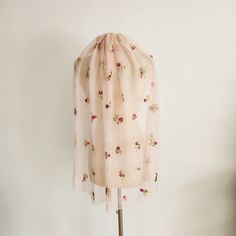 a pink scarf with flowers on it is hanging from a mannequin's head