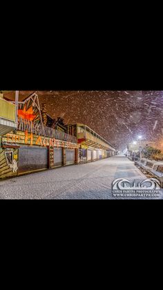 an empty street at night with snow falling