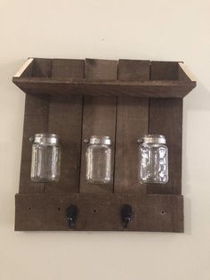 three mason jars are hanging on a wooden shelf