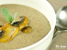 a white bowl filled with soup and topped with a green leaf