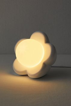 a white cloud shaped light sitting on top of a table next to a wall and floor